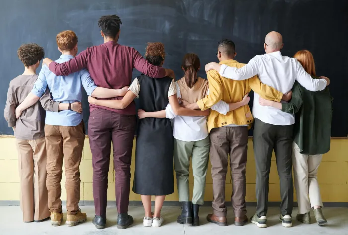 Row of diverse people, standing together with arms around each other's shoulders