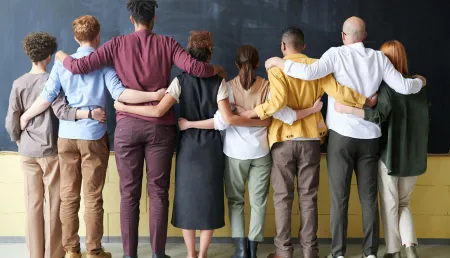Row of diverse people, standing together with arms around each other's shoulders