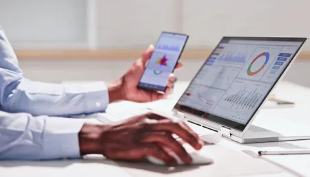 Professional looking at data on laptop and phone